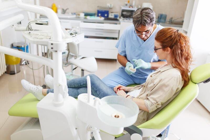 Ein Zahnarzt klärt ein Patientin über die Haltbarkeit von Veneers vs Kronen auf.