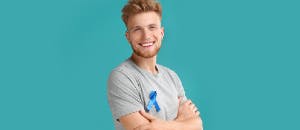 Young man smiling wearing blue ribbon for urologic oncology awareness.